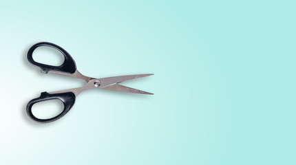 Top view of cutting scissors isolated on a pastel background. Scissors with a black frame and gray knives lie on the table. The concept of cutting, using scissors to cut paper.