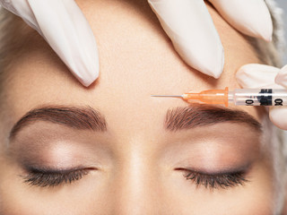 Woman getting cosmetic injection of botox near eyes - obrazy, fototapety, plakaty