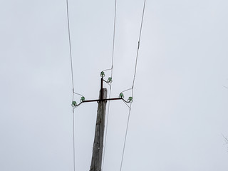 A pole with electrical wires. Wooden pole holding live wires