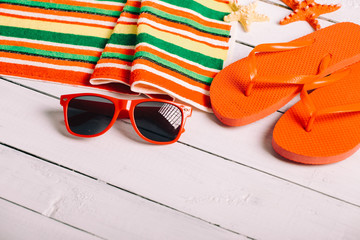 Flip flops, ball, tablet pc, seashell and starfish with tropical flowers on sandy beach