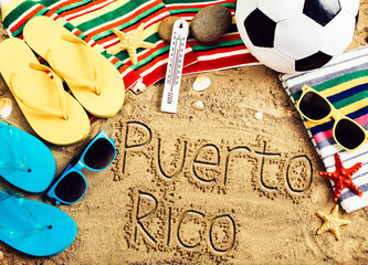 Summer concept of sandy beach, colorful flip flop shoes, sunglasses, ball and inscription puerto...