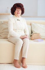 portrait of beautiful mature woman (80 years old) sitting on sofa at home