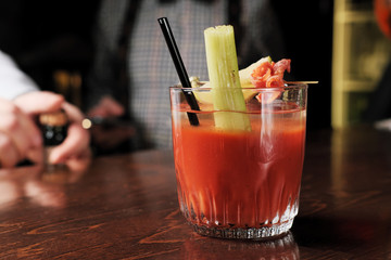 Bloody mary cocktail garnished with celery sticks and olives.