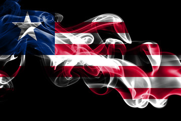 National flag of Liberia made from colored smoke isolated on black background. Abstract silky wave...