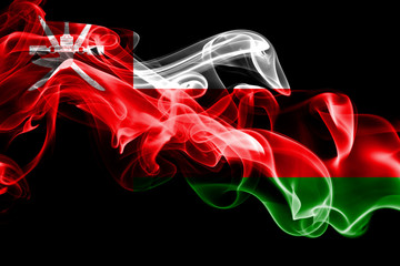 National flag of Oman made from colored smoke isolated on black background. Abstract silky wave background.