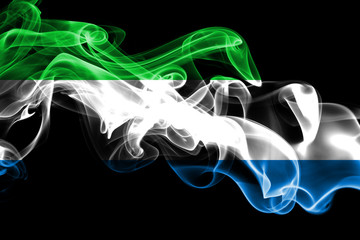 National flag of Sierra Leone made from colored smoke isolated on black background. Abstract silky...