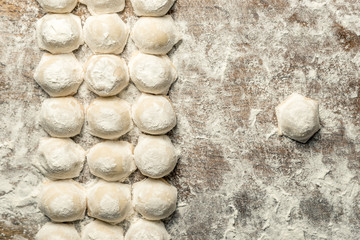 Uzbek national food Chuchvara, like dumplings, on a wooden board, in flour