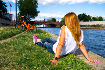 Female tourist relaxing in the grass, gazing at the boats passing under Moltke Bridge...
