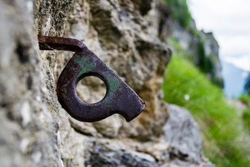 Close up of old bent piton used for mountaineering, fixed into a crack on a rock wall, part of an old climbing route, in Bucegi (Carpathian) mountains, Romania.