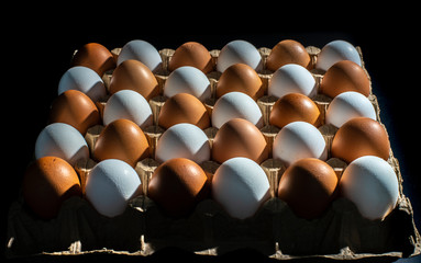 packing of yellow and white chicken eggs arranged in a diagonal composition on a black background