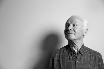Fototapeta premium Portrait of elderly man on light background, space for text. Black and white effect