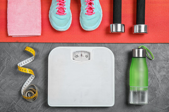 Flat Lay Composition With Scales, Measuring Tape And Sport Equipment On Gray Background. Weight Loss