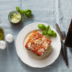 vegan lasagna with lentils and green peas in a baking sheet on a table with a blue linen tablecloth. healthy Italian cuisine for the whole family, party or restaurant and red wine in glasses