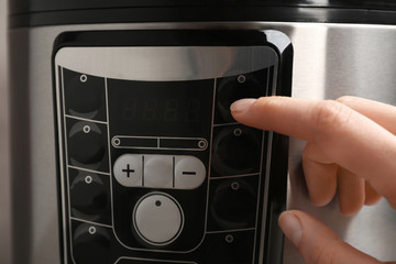 Woman turning on modern electric multi cooker, closeup