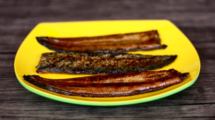 Eel fish or unagi on yellow plate with wood background. Ready to cook. 