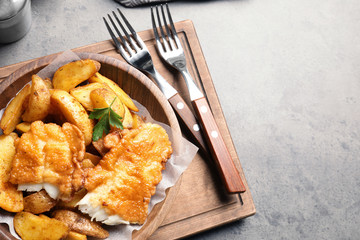 Wooden plate with British traditional fish and potato chips on table. Space for text