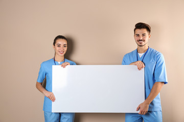 Medical students with blank poster on color background. Space for text