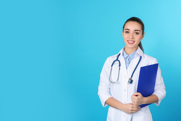 Fototapeta premium Young medical student with clipboard on color background. Space for text