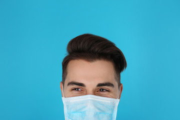 Young medical student with face mask on color background, closeup