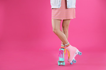 Young woman with retro roller skates on color background, closeup. Space for text