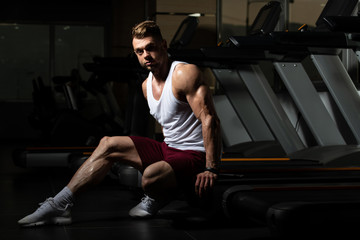 Fototapeta na wymiar Male Resting On Bench In Fitness Center