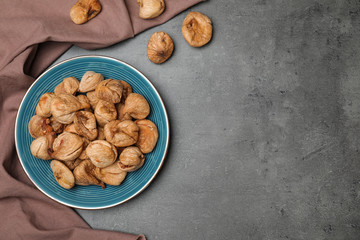 Plate of dried figs on grey background, top view with space for text. Healthy fruit