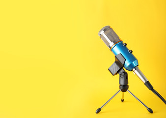 Condenser microphone on color background, space for text