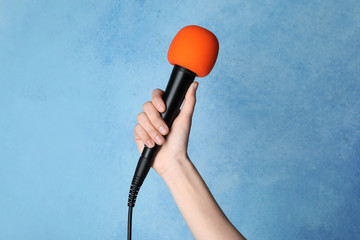 Woman holding microphone on color background, closeup