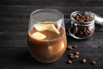 Coffee drink with milk ice cubes and beans on dark background
