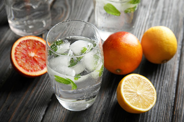 Glass of drink with ice cubes and fruits on wooden table