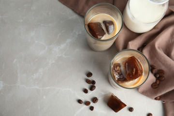 Glasses of milk with coffee ice cubes on grey table, top view. Space for text