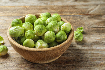 Bowl of fresh Brussels sprouts on wooden background. Space for text