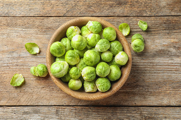 Bowl of fresh Brussels sprouts on wooden background, top view