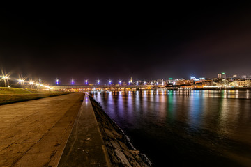 Belgrade, Serbia - February 10, 2019: A panorama of Belgrade seen from the banks of the Sava River by night with reflection. View of the Brankov Bridge. 