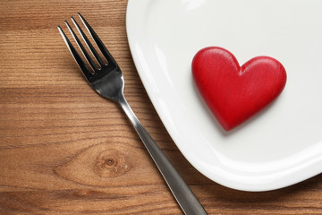 Plate with red heart, fork and space for text on wooden table, flat lay. Healthy diet concept