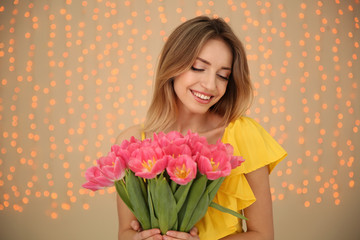 Portrait of smiling young girl with beautiful tulips on blurred background. International Women's Day