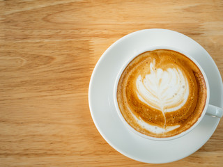 Cup of latte art coffee on wooden table, top view