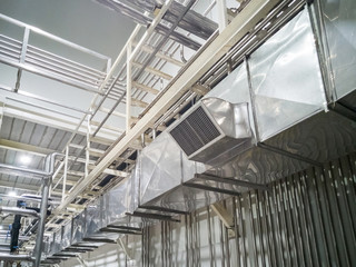 Industrial air duct ventilation equipment and pipe systems installed on industrial building ceiling.