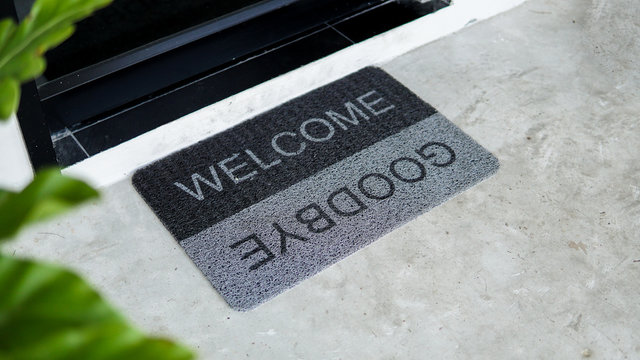 Front Door With Doormat Plants With Welcome,goodbye Written On It