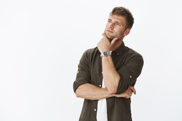 Thoughtful and smart good-looking creative male imaging, making up new idea or feeling nostalgic...