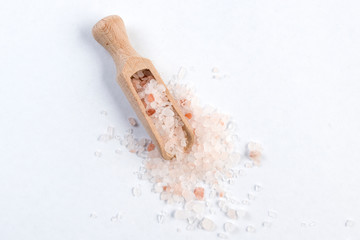 Himalayan pink salt  in wooden scoop isolated on white background. Closeup.