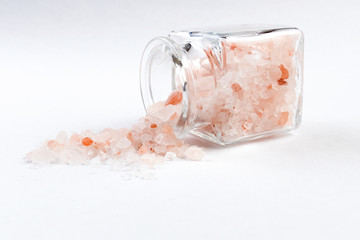 Himalayan pink salt  in a glass jar isolated on white background