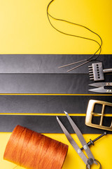 Leather crafting tools lie on black leather stripes. Leather workshop of making leather goods