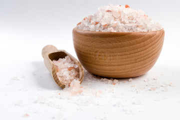 Himalayan pink salt  in wooden bowl and scoop isolated on white background. Closeup.