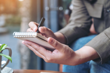 Closeup image of a woman's hands holding and writing on blank notebook