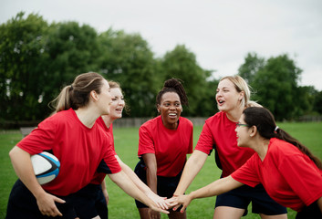 Female rugby players stacking their hands together