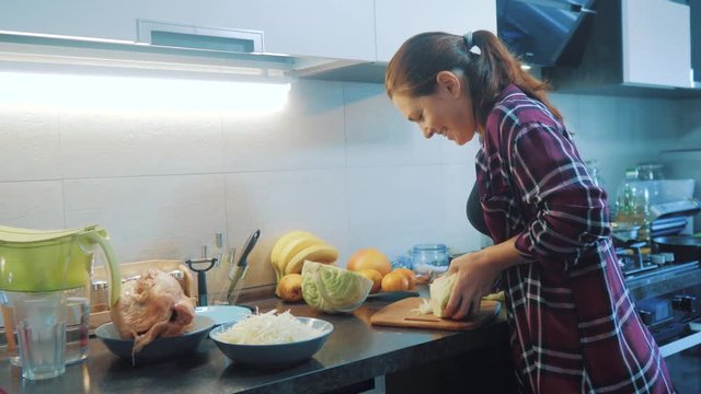 woman in the kitchen preparing a meal concept. girl in lifestyle the kitchen cuts cabbage with a knife. cook vegetarian food healthy food. girl at home in the kitchen slow motion video