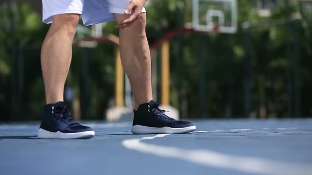 close-up shot of asian male basketball player dribbling on outdoor court