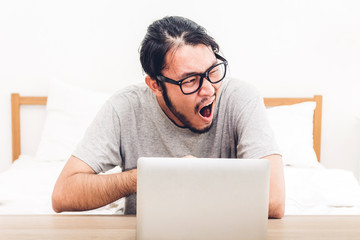 Man using digital laptop computer on the bed at home.man checking social apps and working.wireless technology concept