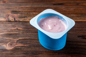 Yogurt with wild berries on dark wooden background.